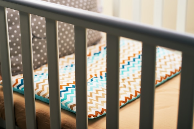 empty white crib and colorful pillow