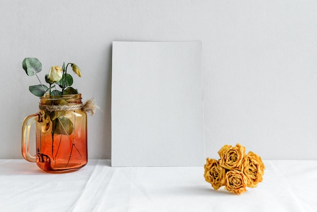 An empty white greeting card and dried flowers in a vase on a white background Romantic background for the invitation