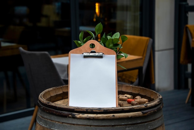 Empty white paper menu on restaurant entrance Modern and cozy cafe or bar facade with tables and chairs on outdoor patio