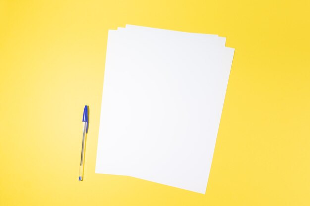 Empty white paper sheet and a pen on yellow background mockup