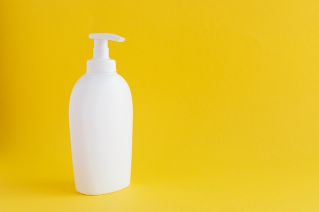 An empty white plastic bottle on a yellow background