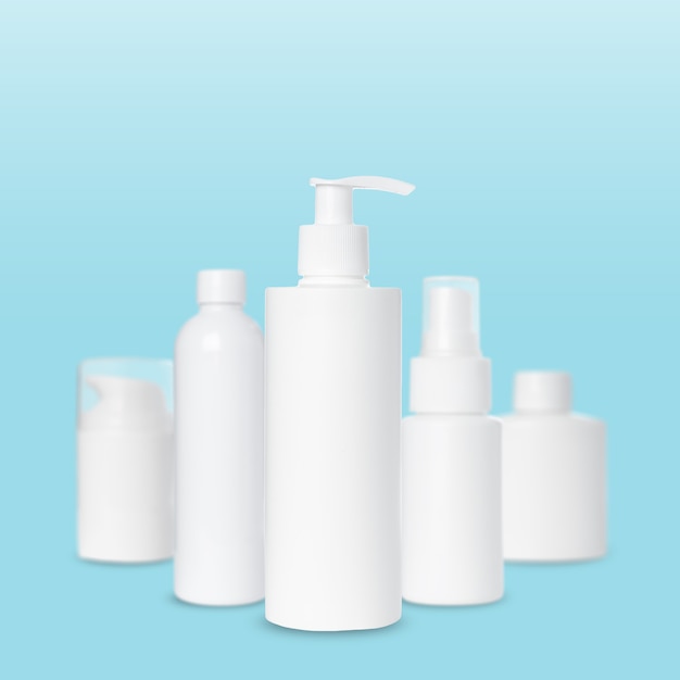 Empty white plastic bottles for cosmetics on blue background. Mockup