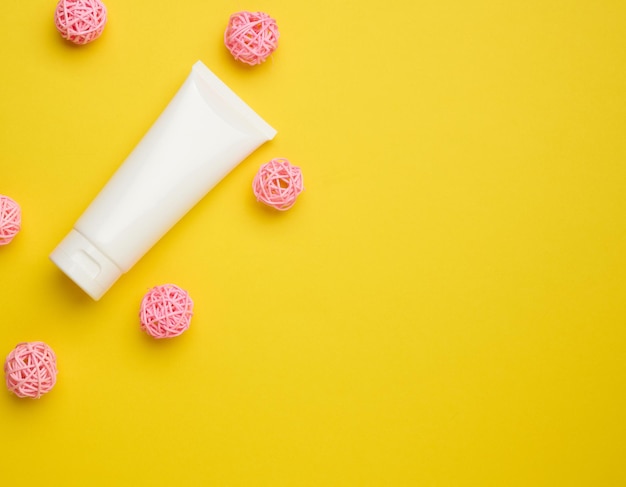 Empty white plastic tubes for cosmetics on a yellow background packaging for cream gel