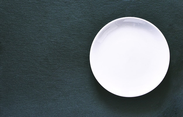 Empty white plate on black slate board