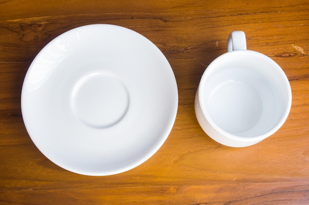 Empty white plate and coffee cup on wooden background