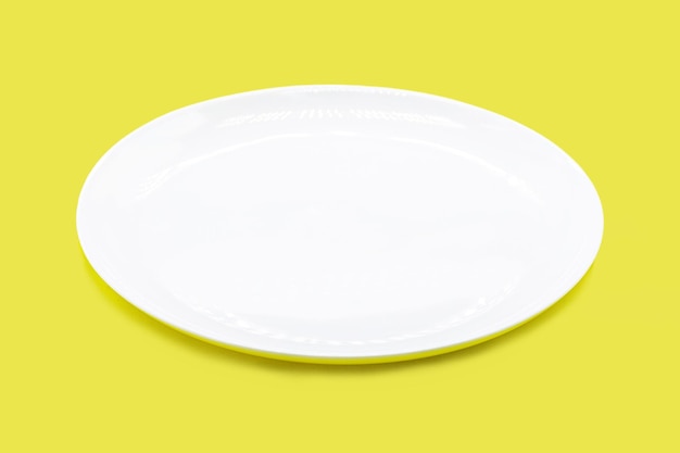 Empty white plate on isolated yellow background space for text copyspace