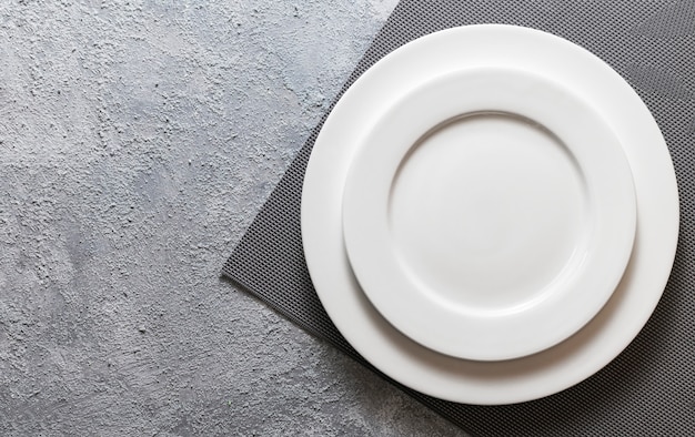 Фото Пустая белая тарелка подается на рельефной салфеткой и тиснением серый бетонный фон. вид сверху макет для меню