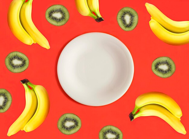 Photo empty white plate for text banana and kiwi on the red background top view copy space