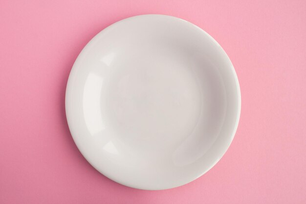 Empty white plate for text on the pink background Copy space Top view