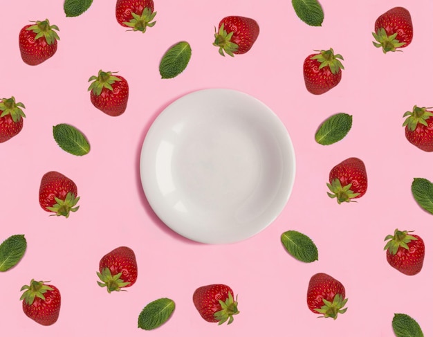 Empty white plate for text strawberry and mint on the pink background Top view Copy space