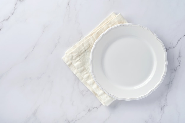 Empty white plate and towel over white marble table for your recipe or menu.