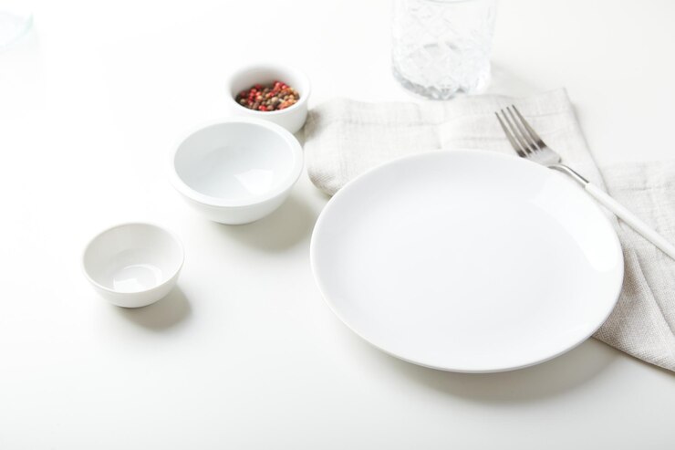 Photo 밝은 배경에 포크와 작은 그릇이 있는 빈 흰색 접시