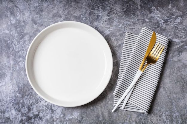 Foto piatto bianco vuoto con tovagliolo per ricette alimentari e menu ristorante su tavolo in pietra e sfondo scuro. vista dall'alto. design piatto.