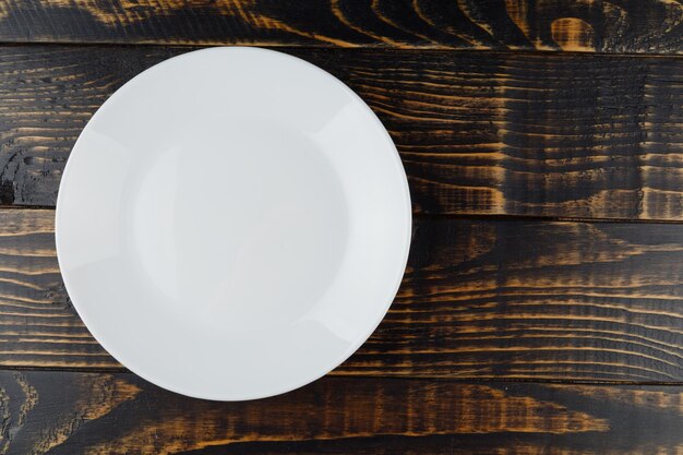 Empty white plate on wooden background