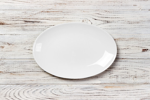 Empty white plate on wooden table. top view