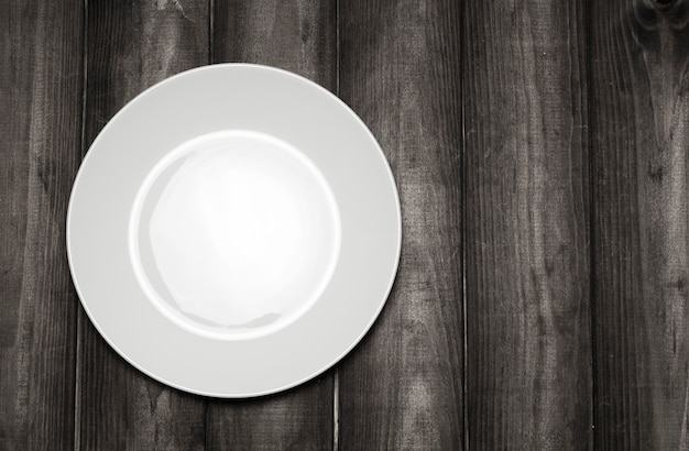 Empty white plate on a wooden table top