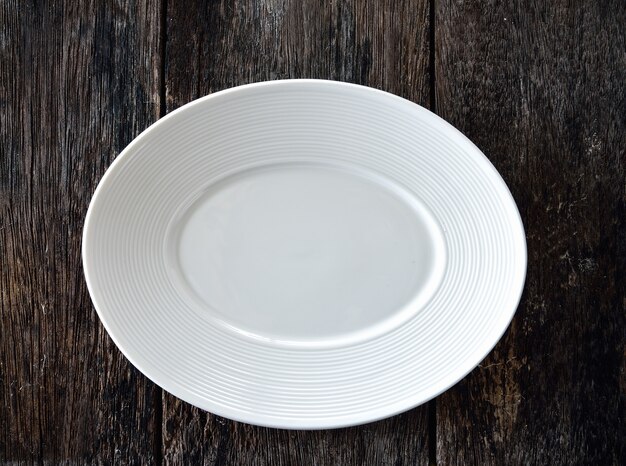 Empty white plate on wooden