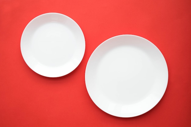 Empty white plates on a red table, top view