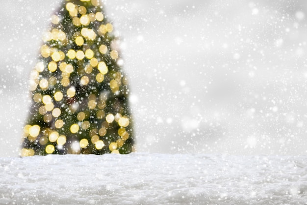 ボケの明るい背景のぼんやりした白い雪とクリスマスツリー