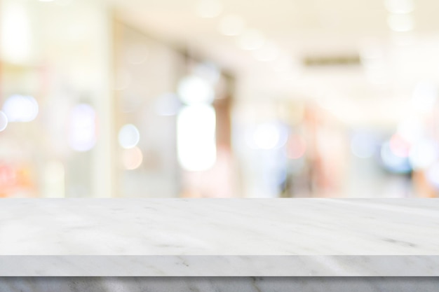 Empty white table top counter desk over blur perspective store with bokeh light background