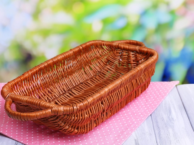 empty wicker basket on wooden table on bright background