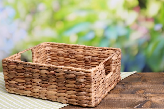 empty wicker basket on wooden table on bright background