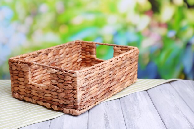 empty wicker basket on wooden table on bright background