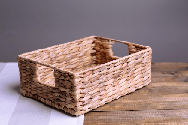 empty wicker basket on wooden table on dark background