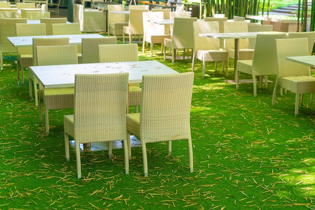 empty wicker table and chair in outdoor restaurant with bamboo forest garden