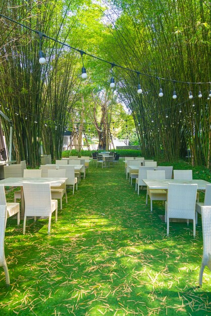 empty wicker table and chair in outdoor restaurant with bamboo forest garden