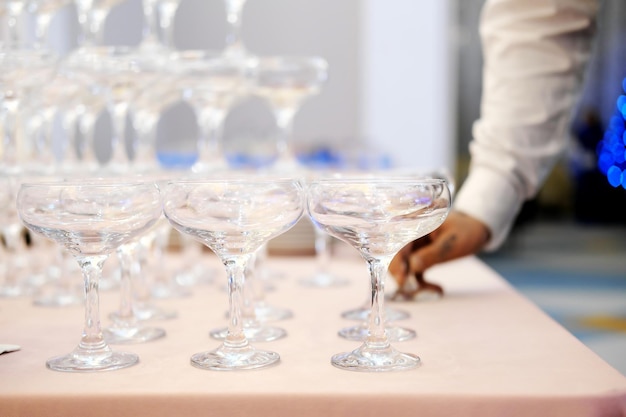 Photo empty wine or champagne glasses on table are in pyramid the waiter arranges glasses in a pyramid