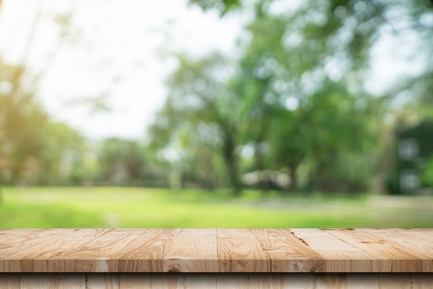 Tavolo in legno vuoto e bokeh sfocato e sfocatura dello sfondo di alberi da giardino con luce solare. modello di visualizzazione del prodotto.