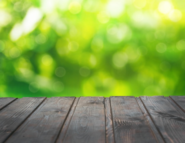 Piano d'appoggio di legno vuoto sulla sfocatura giardino verde astratto di mattina.