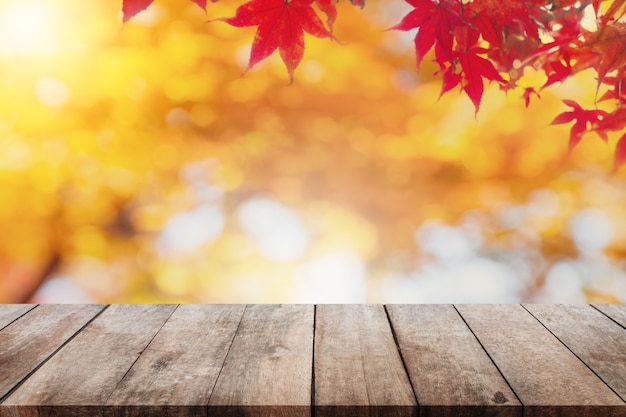 空の木のテーブルのトップと秋の木と紅葉の背景がぼやけ