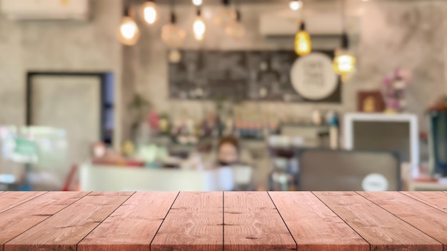 Foto il piano del tavolo in legno vuoto e lo sfondo sfocato della caffetteria e del ristorante possono essere utilizzati per visualizzare o montare i tuoi prodotti