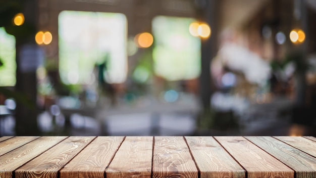 Empty wood table top and blurred coffee shop, cafe and restaurant interior background.