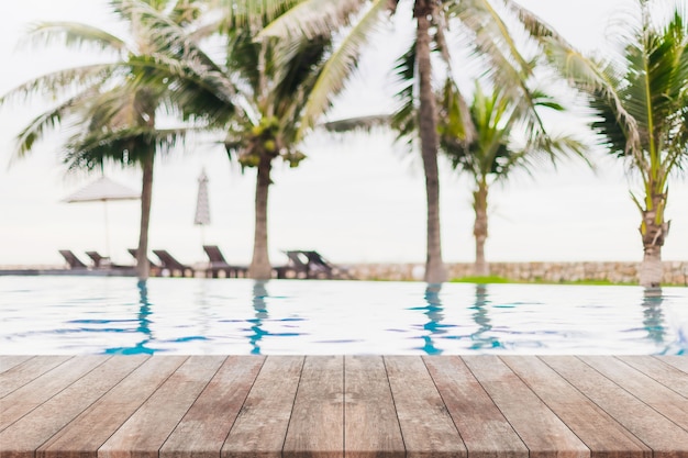 Foto piano d'appoggio in legno vuoto e piscina sfocata nella località tropicale in estate