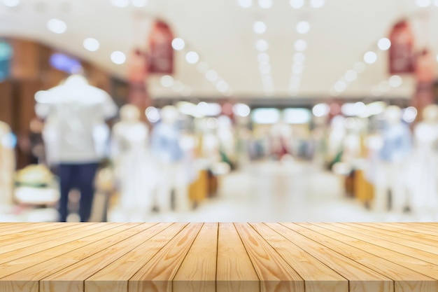 Empty wood table top with blur clothing boutique display interior shopping mall background