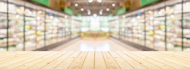 Empty wood table top with supermarket grocery store aisle and shelves blurred background