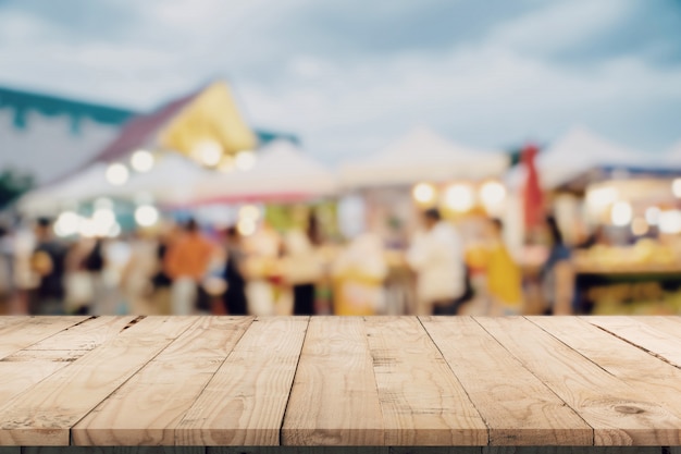 Foto la tavola di legno vuota e il tono d'annata hanno offuscato defocused della gente della folla nel festival e nel centro commerciale ambulanti della via.