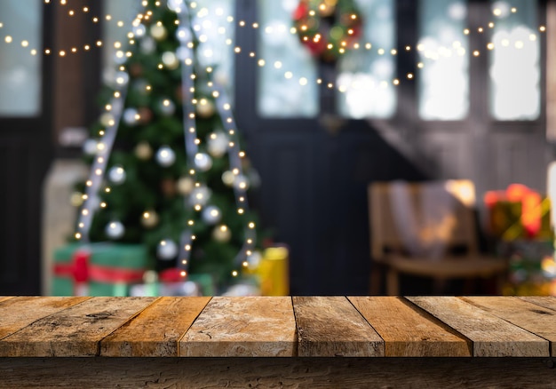 Tavola di legno vuota con l'albero di natale decorato con fondo brillante delle luci sfocato