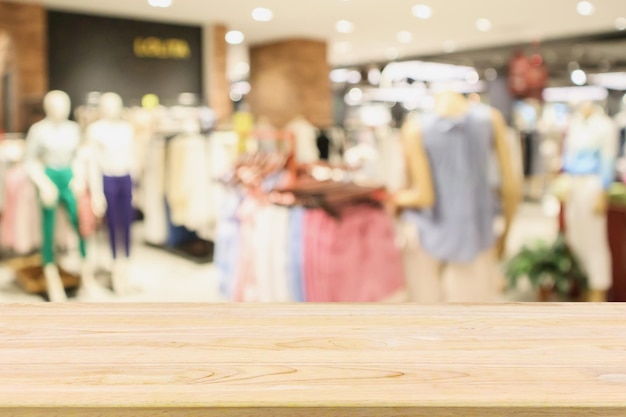 Tavolo in legno vuoto con vetrina del negozio di abbigliamento boutique alla moda donna nel centro commerciale