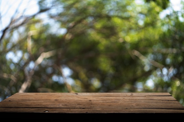 Empty wooden board on table top and blur inside abstract green background with natural bokeh mock up for display of goods