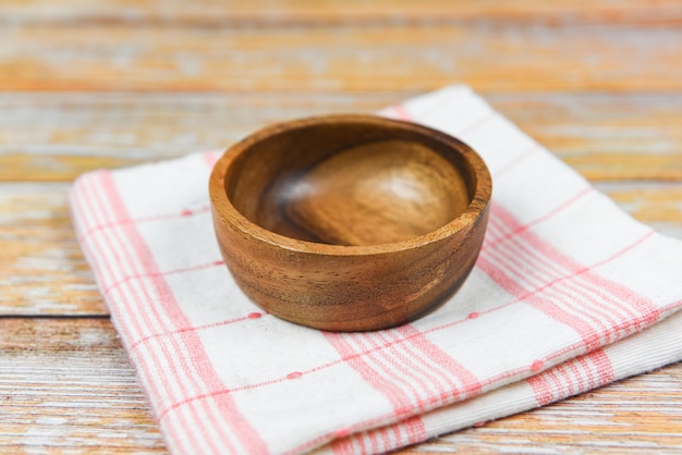 Empty wooden bowl on tablecloth napery on dining table