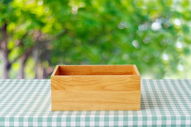 Empty wooden box on table with green scott pattern tablecloth 