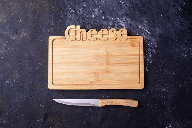 Photo empty wooden cheese board  a knife. top view.