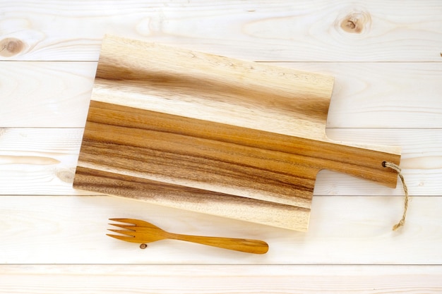 Empty wooden chopping board and fork on table, background