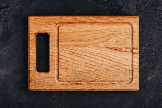 Empty Wooden Chopping or Cutting Board on dark stone concrete background top above view