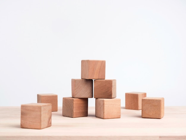 Empty wooden cube blocks on the table on white background with copy space. Many wood bricks building tower construction. Mockup composition for design.