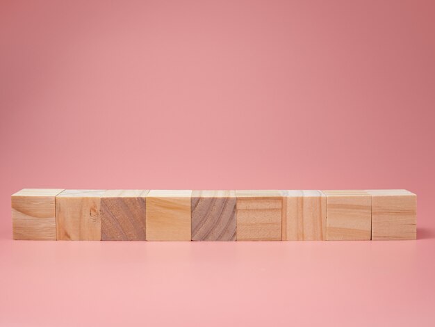 ピンクの背景に並んでいる空の木製キューブ。新しいアイデアを写真に入れてください。